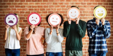 5 Menschen mit unterschiedlich emotionalen Smileys vor dem Gesicht