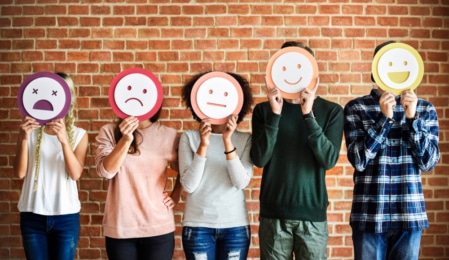 5 Menschen mit unterschiedlich emotionalen Smileys vor dem Gesicht
