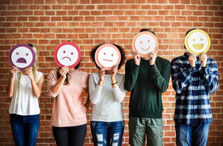 5 Menschen mit unterschiedlich emotionalen Smileys vor dem Gesicht