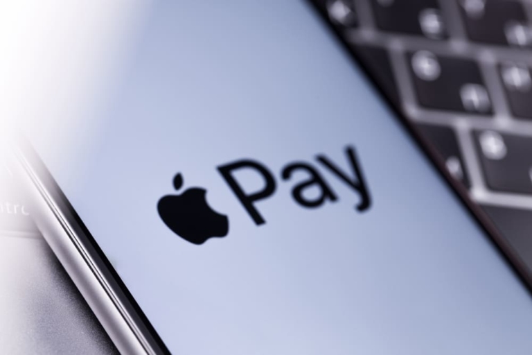 Zu sehen ist ein Apple iPhone mit Apple Pay Logo auf dem Display auf einer Tastatur.