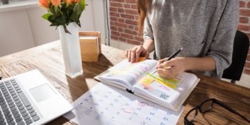 Frau mit Kalender am Tisch, Terminplanung