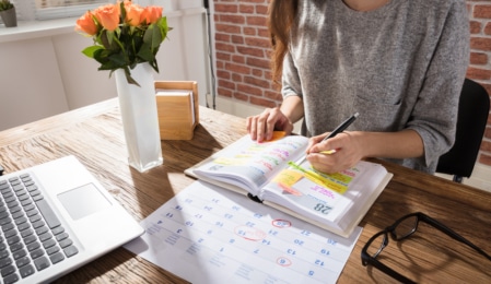 Frau mit Kalender am Tisch, Terminplanung