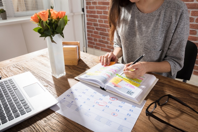 Frau mit Kalender am Tisch, Terminplanung