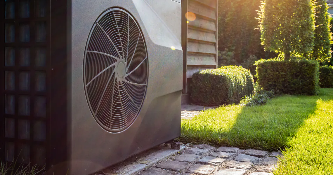 WärmepumpenSEO: Nahaufnahme einer schwarzen Inverter-Wärmepumpe draußen im Garten.